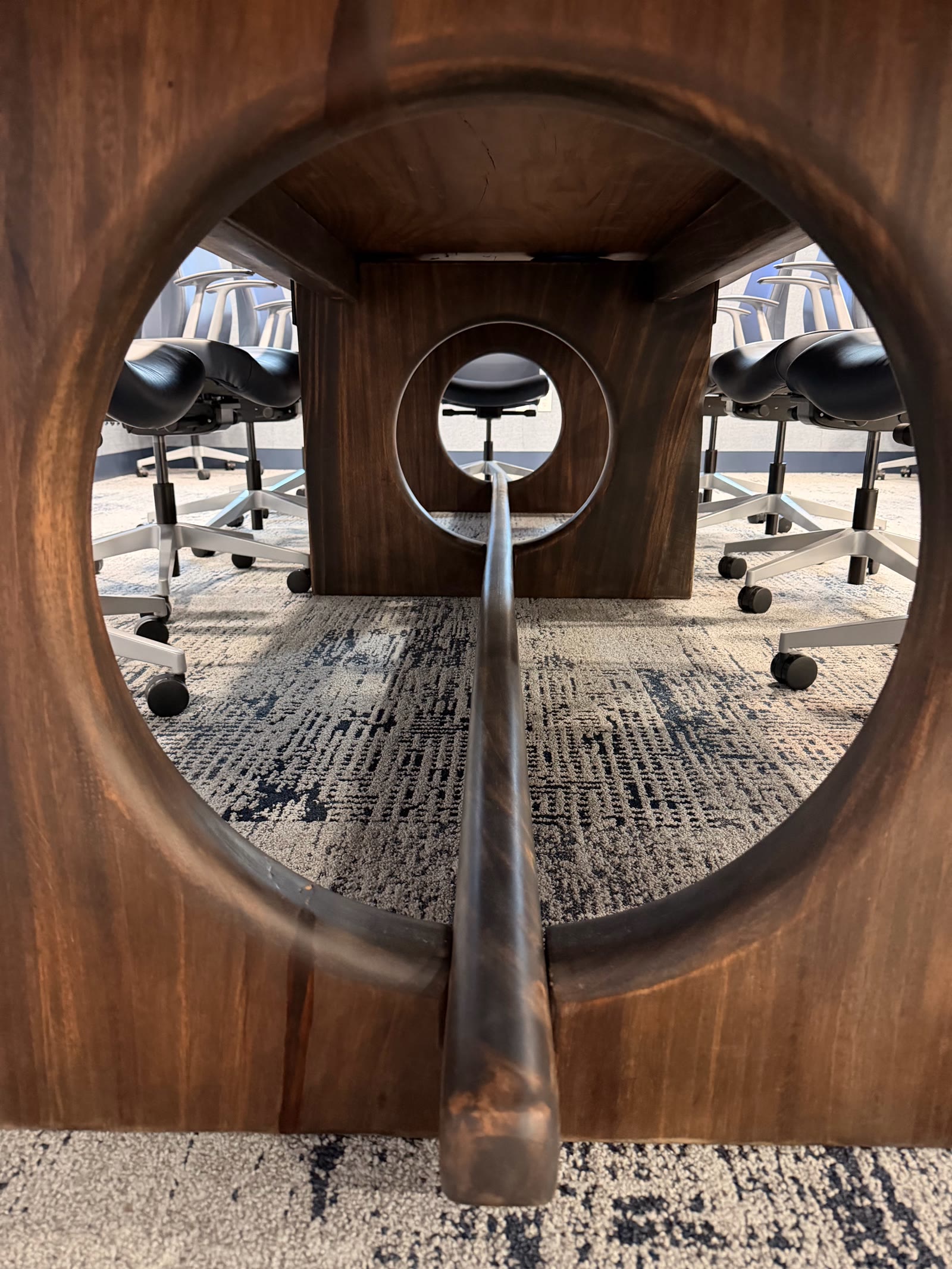 Hollowed conference table leg base with circular cutouts for hidden wiring