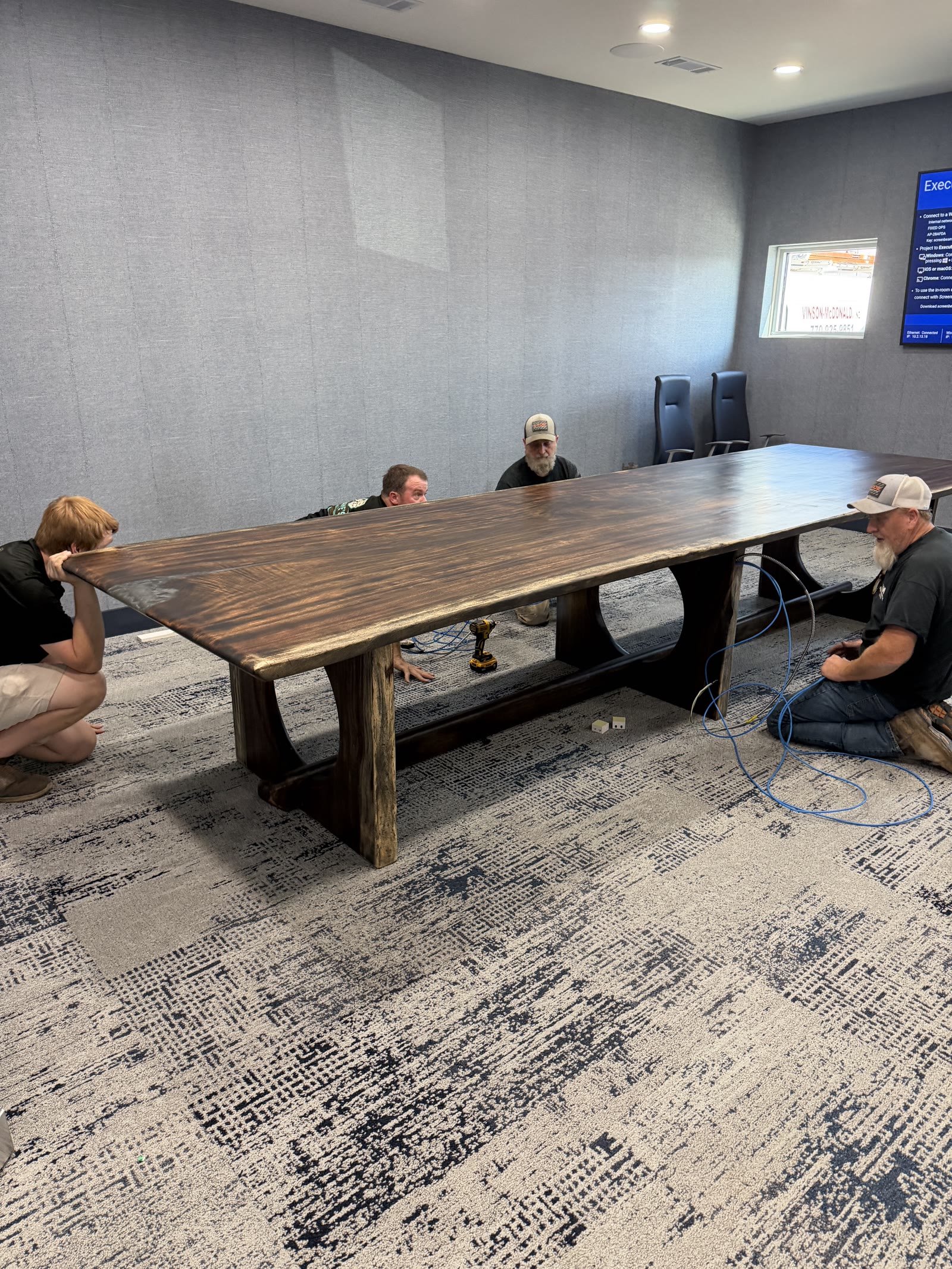 Crew setting the live-edge Akins Ford conference table in place, from our Statham, GA shop