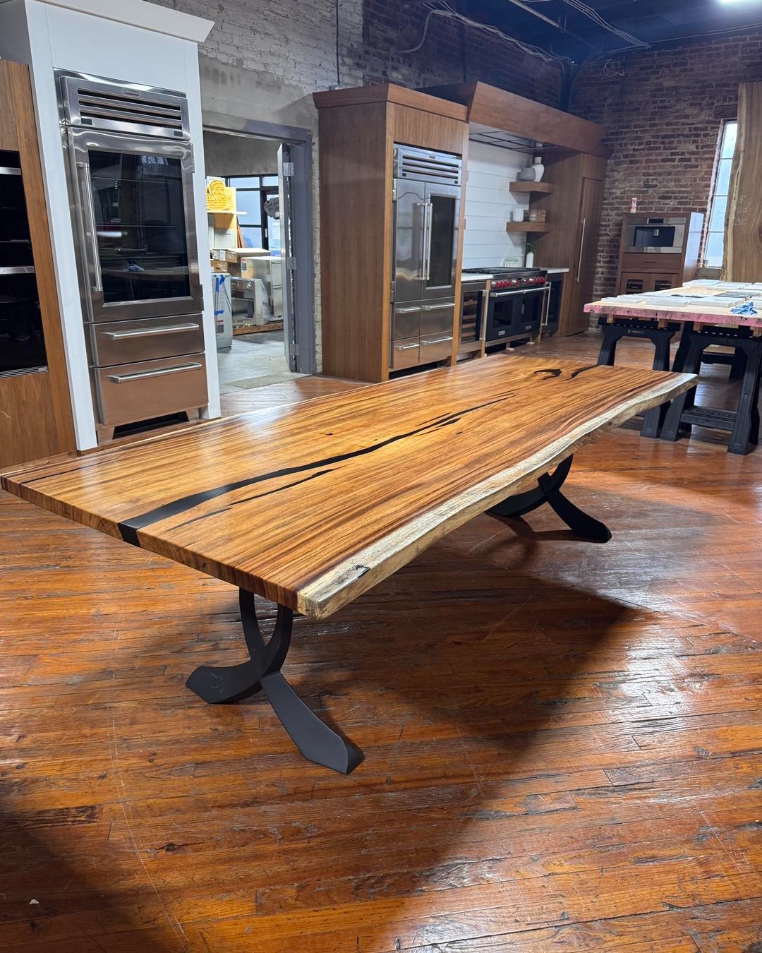 Finished live-edge dining table with black epoxy-filled cracks, on black steel legs, from our Statham, GA shop