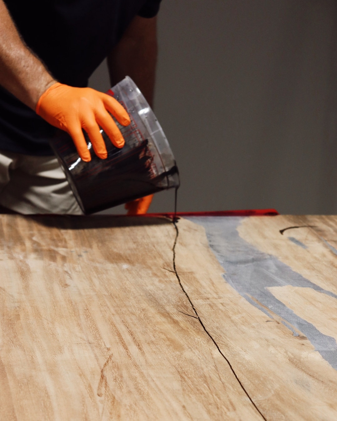 Pouring black epoxy resin into a crack in a wood slab, from our Statham, GA shop