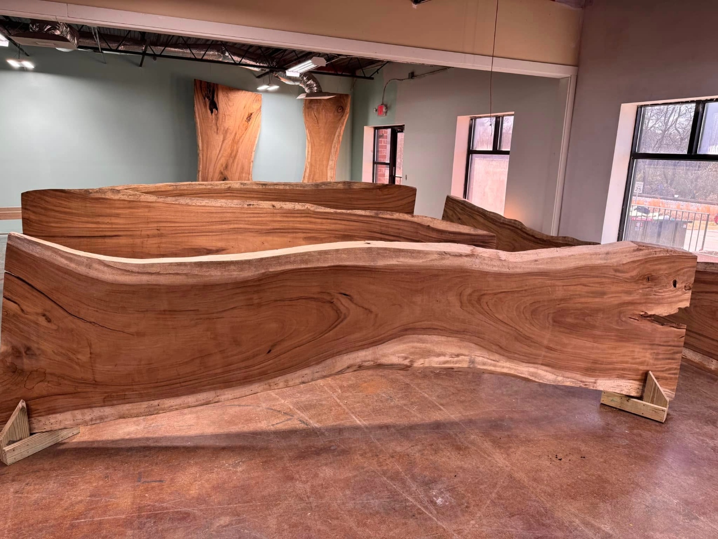 Live-edge slabs with natural curved edges stacked in the workshop