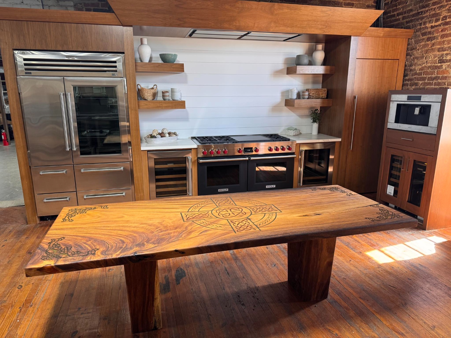 Finished wood dining table with a carved Celtic knot design in a kitchen showroom, from our Statham, GA shop