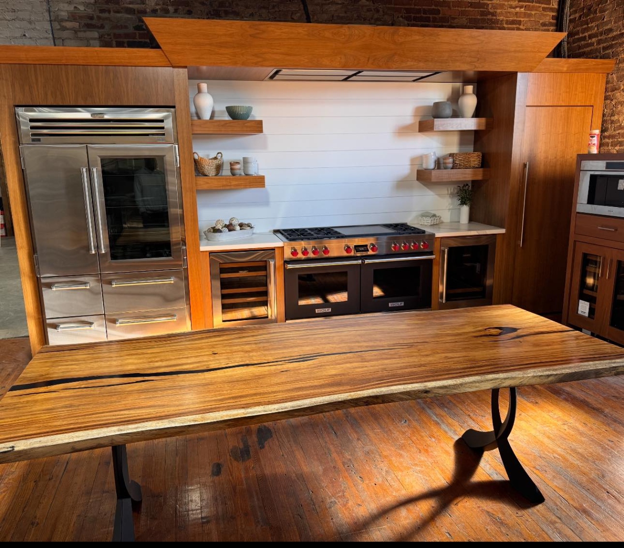 Finished live-edge dining table on a black steel base in a kitchen showroom, from our Statham, GA shop