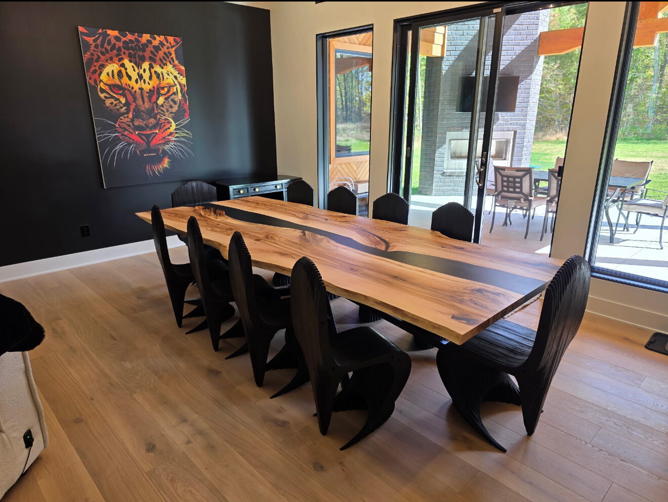 Long live-edge table with a resin river, lined with black chairs