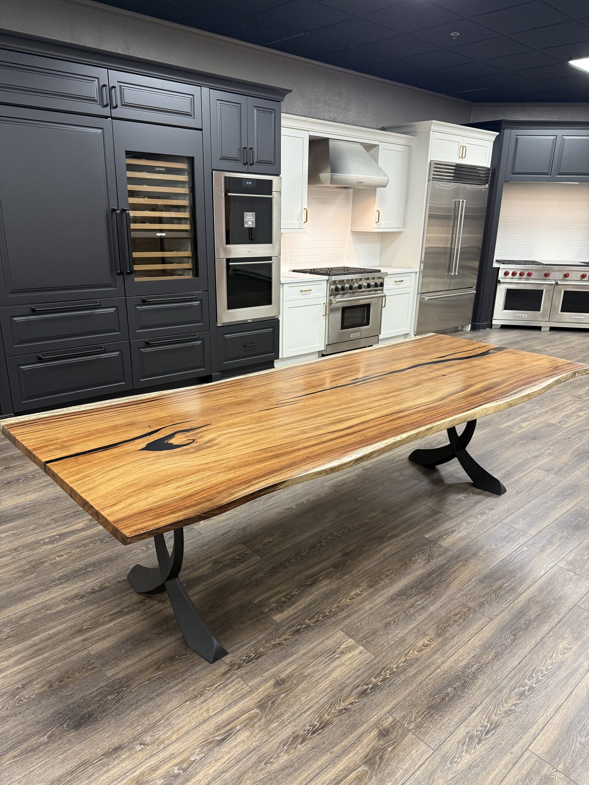 Live-edge resin river dining table on black steel legs in a kitchen showroom