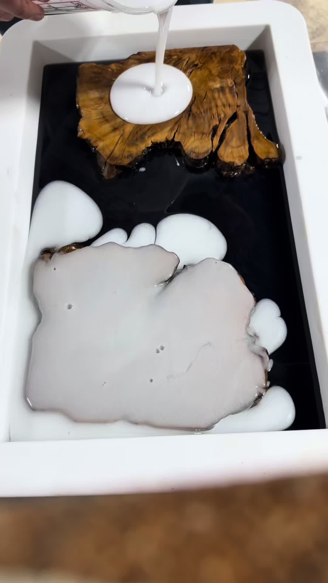 White resin pour in progress in the workshop