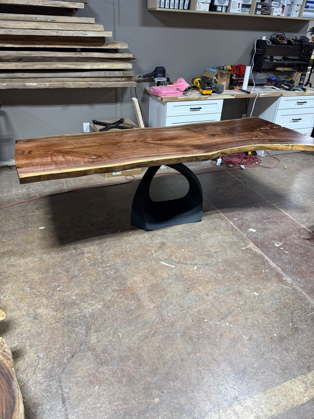 Live-edge black walnut desk with butterfly joints on a sculpted black pedestal base with a teardrop cutout
